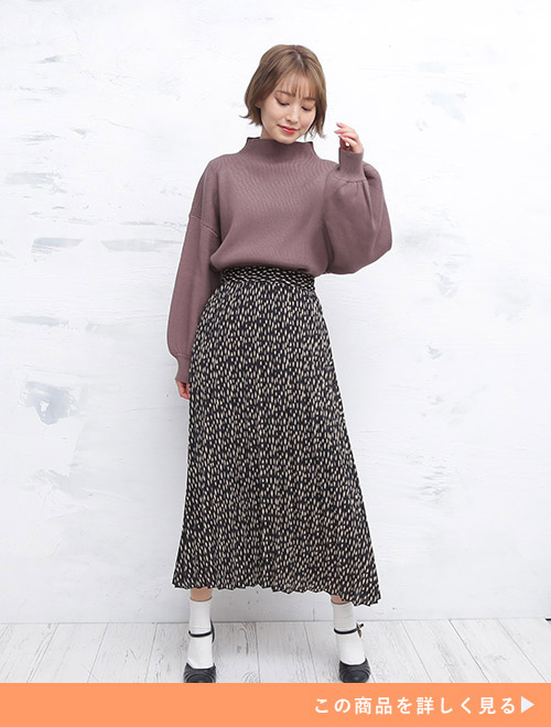 白のドット柄×黒地のロングスカートに、モカ色のトップスをタックインして着る女性