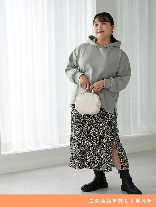 ブルーグレーのフーディーを着て、黒色のヒョウ柄スカートを履く女性