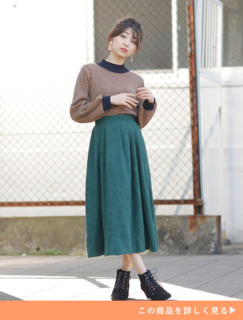 グリーンのタックスカートに細ボーダーのトップスをインして着る女性