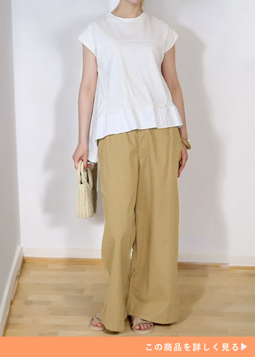 ベージュのワイドパンツに白の半袖トップスを着た女性
