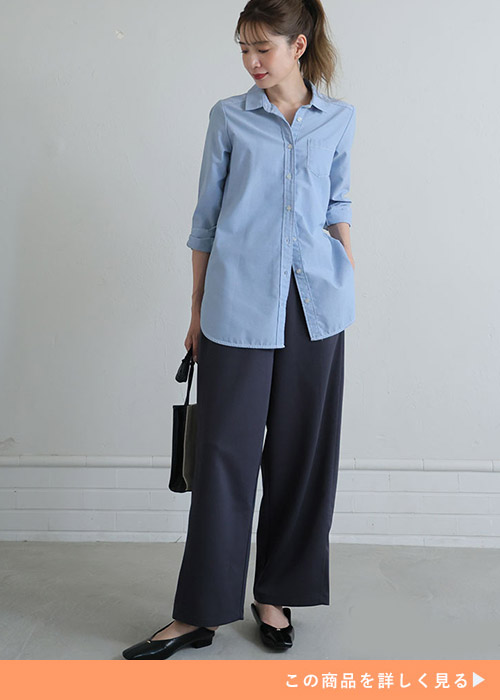ネイビーのワイドパンツに水色のシャツを着る女性