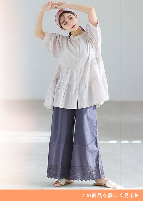 チャコールカラーのワイドパンツにベージュのギャザーシャツを合わせた女性