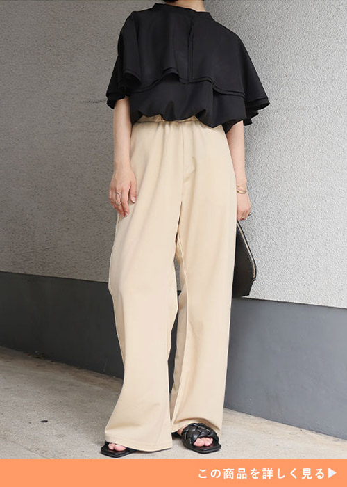 ベージュのワイドパンツに黒のデザイントップスを着る女性