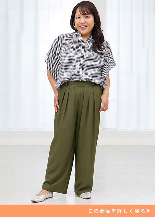 カーキのワイドパンツにギンガムチェックのシャツを着る女性