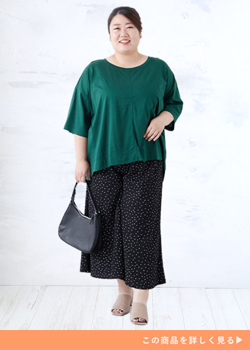 ブラックのドット柄ワイドパンツにグリーンのトップスを着る女性