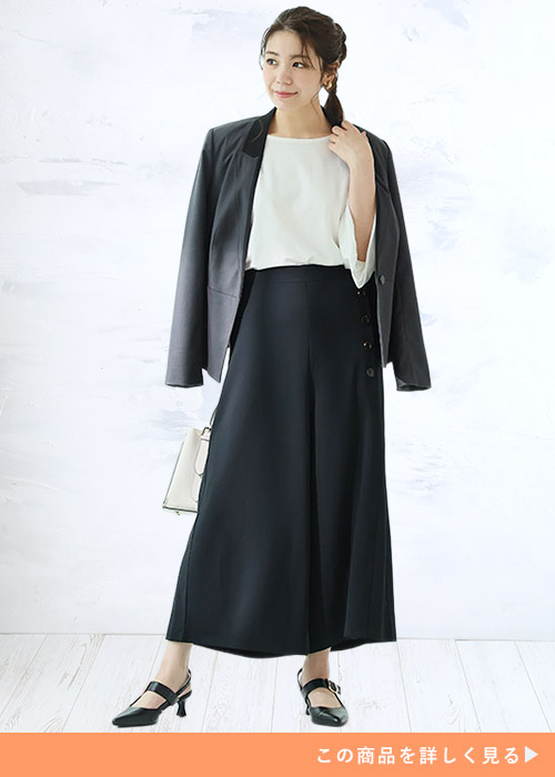 黒のワイドパンツに白シャツを着た女性