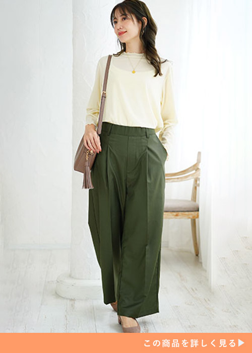 カーキのワイドパンツに白トップスを着た女性