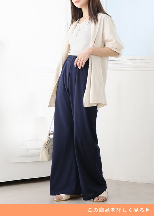 ネイビーのカラーワイドパンツにタンクトップを着て、ベージュのカーディガンを羽織った女性