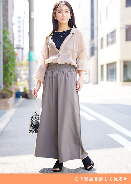 グレーのワイドパンツに黒のTシャツとベージュのシャツ、トップスインした女性