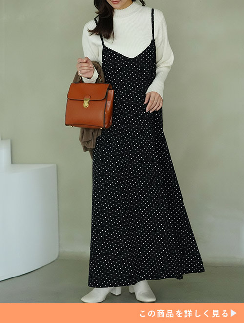 ホワイトタートルニットトップスにブラックドットキャミワンピをレイヤードする女性