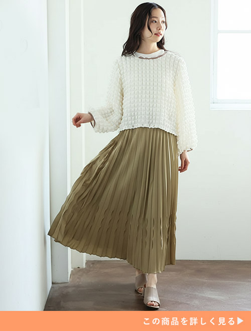 ホワイトトップスとピスタチオカラーのプリーツスカートのコーデにベージュミュールを履く女性