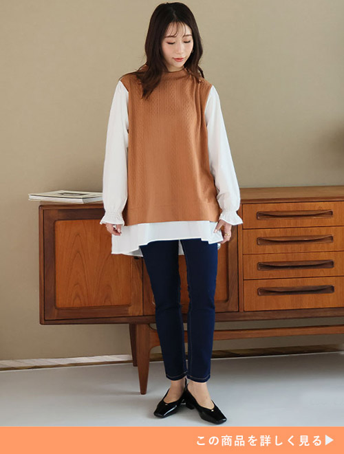 ホワイトシャツのモカベストのレイヤード風トップスにデニムスキニーパンツを履く女性