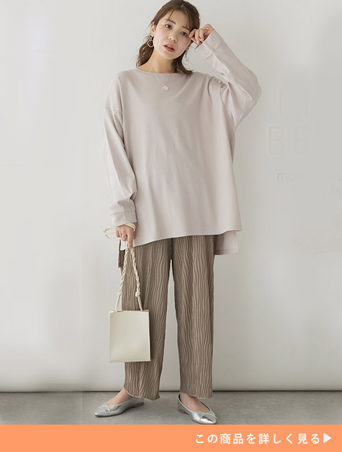 ピンクベージュのドルマンスリーブカットソーにベージュのパンツを合わせる女性