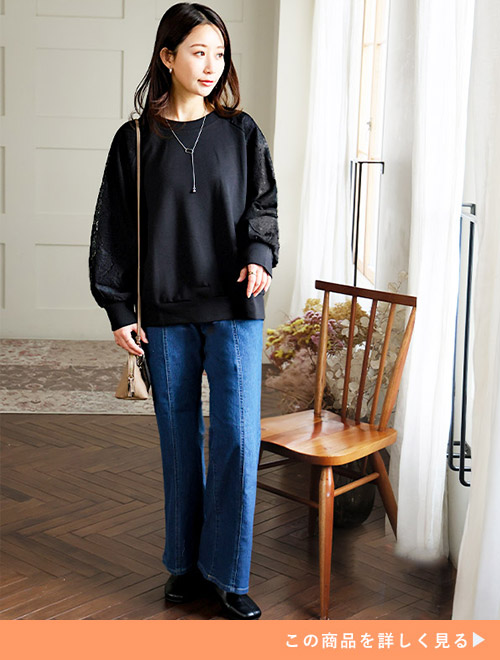 ブラックのドルマンプルオーバーにセンタープレスデニムパンツを履く女性
