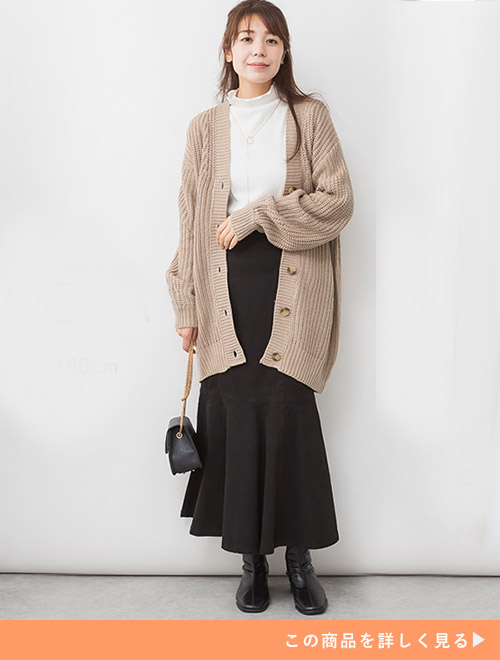 ホワイトトップスとブラックマーメイドスカートのコーデにモカのニットカーデを羽織る女性