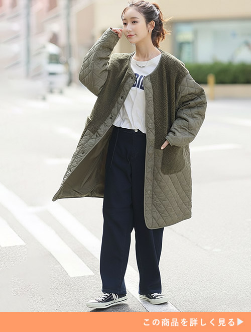 ホワイトTシャツとブラックパンツのコーデにカーキのキルティングコートを羽織る女性