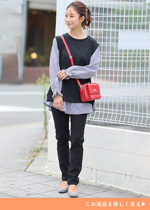 チェック柄シャツ×黒ベストのトップスに黒のスキニーパンツを履く女性