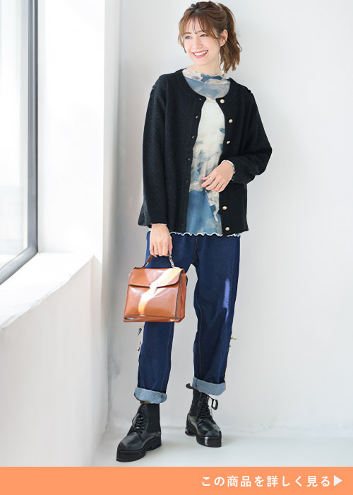 柄シアートップス×黒のツイード風ニットジャケットを着て、デニムを履く女性