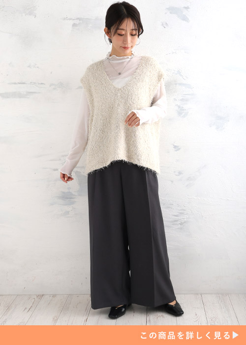 白のシアートップス×Vネックベストを着て、黒のワイドパンツを履く女性