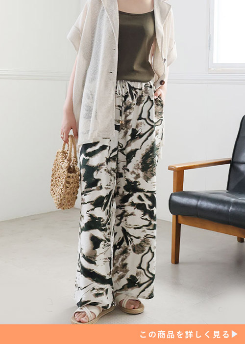 ブラウンのキャミ×総柄イージーパンツに、ベージュのシアーシャツを羽織る女性