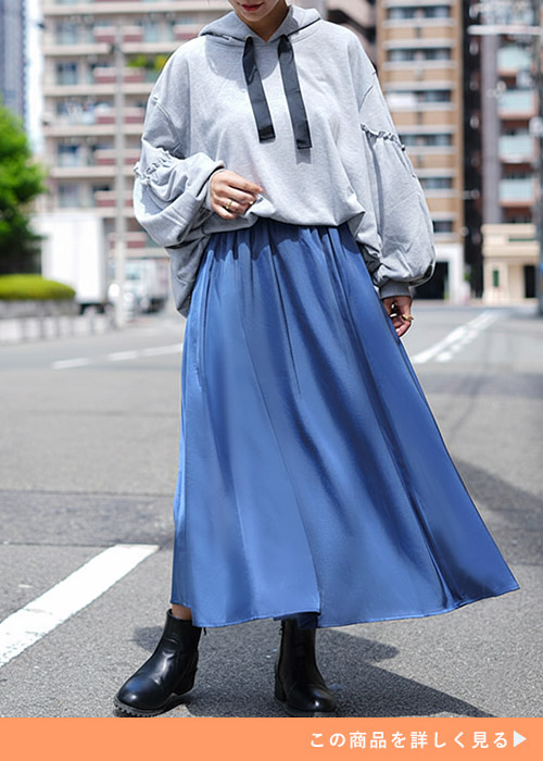 グレーのパーカ×ブルーのサテン生地フレアースカートを着る女性