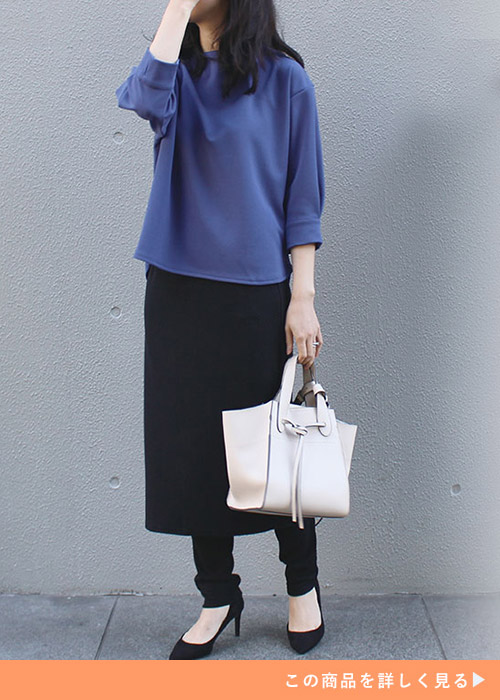 ブルーのトップスを着て、スカート×レギンスのセットを履く女性