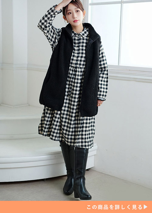 チェック柄ワンピに黒のボアベストを着る女性