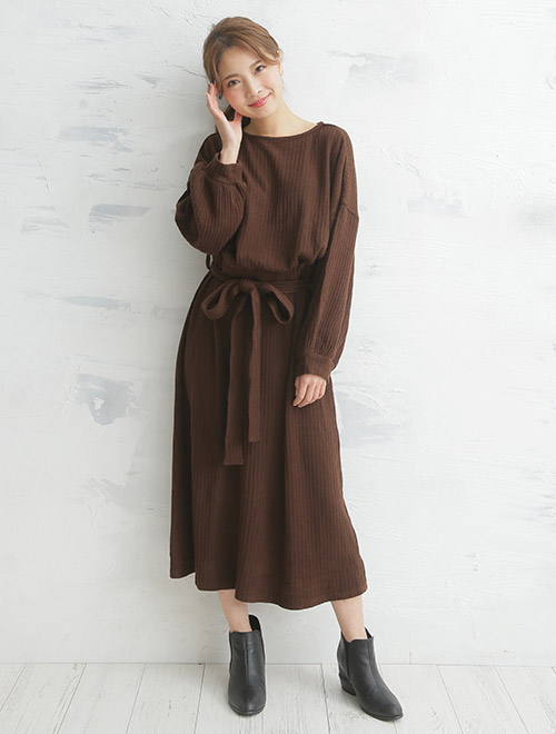 ブラウンのベルト付きニットワンピを着る女性