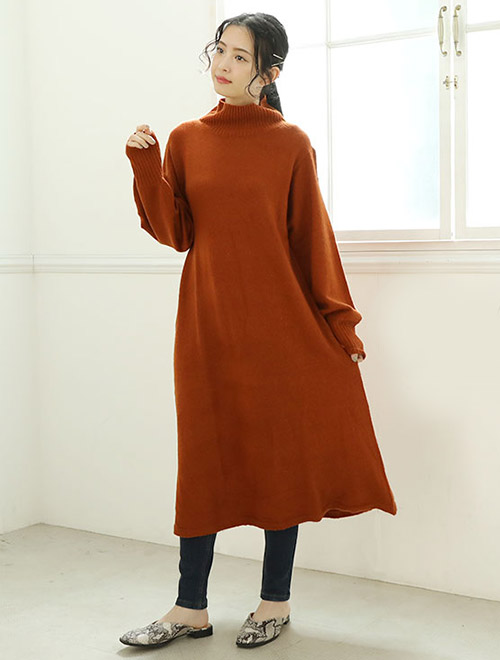 ブラウンのフレアーニットワンピースを着て、下にレギンスを履く女性