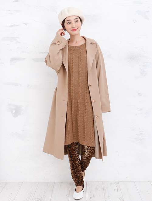 ブラウンのニットワンピースにアニマル柄レギンスを合わせて、キャメルのコートを羽織る女性