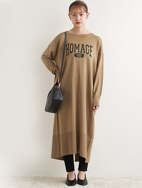 ロゴ入りロングニットワンピースに、黒のレギンスを合わせた女性