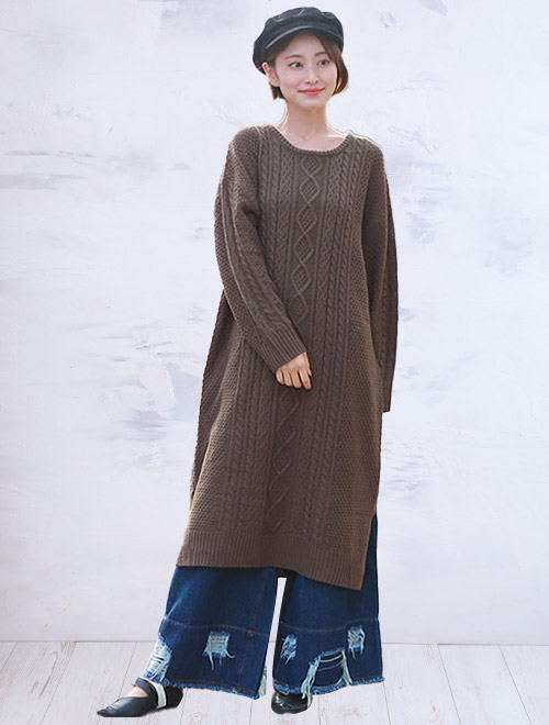 ケーブル編みニットワンピを着て、ダメージ加工ワイドデニムを合わせた女性
