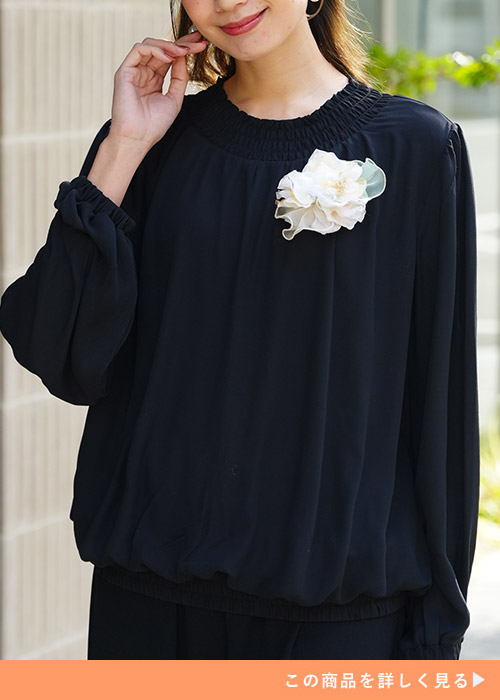 ブラックのシャーリングブラウスとワイドパンツのセットアップを着る女性