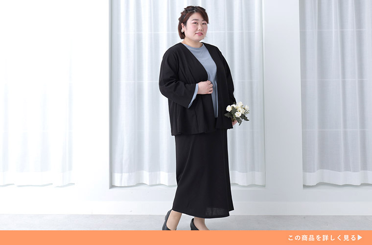 くすみブルーのトップスに、黒のジャケット×ナロースカートを着る女性