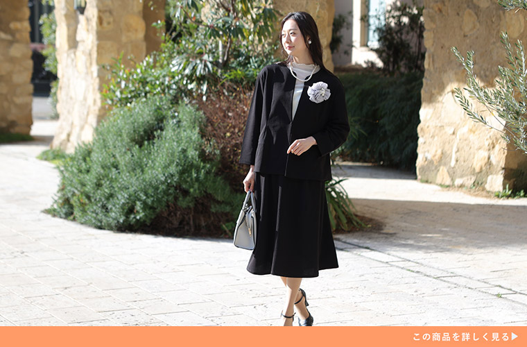 白のシースルートップスを着て、ベージュのワイドパンツを履く女性