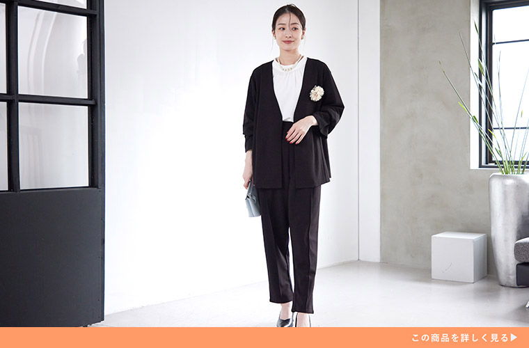 白色のブラウスに、テーバードパンツ×ジャケットを着る女性