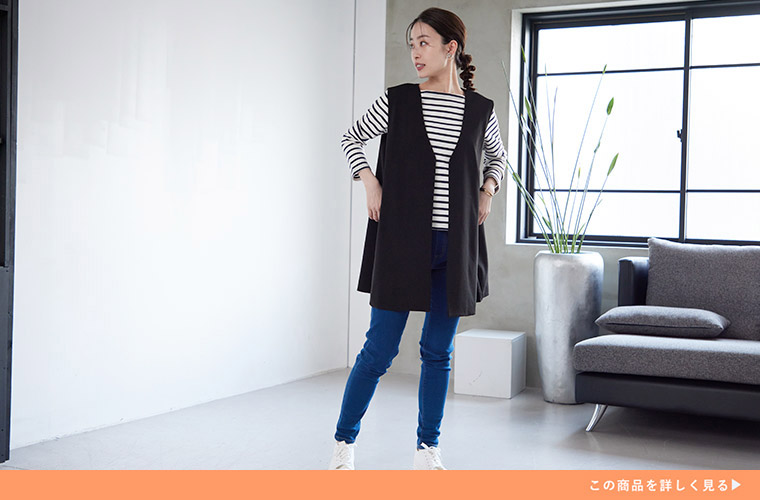 白黒のボーダーTシャツ×デニムに、黒色のジレを重ね着する女性