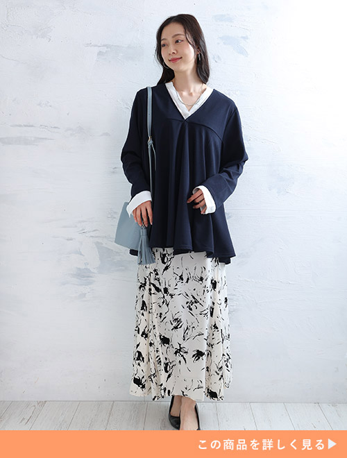 白シャツ×白黒の花柄スカートに、ネイビーのジャケットを羽織る女性