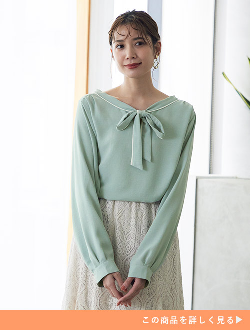 ミントグリーンのボウタイブラウスを着て、レーススカートを履く女性。