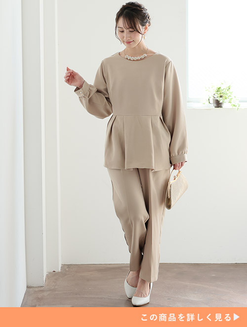 ウエストタックのペプラムトップス×パンツのベージュのセットアップを着る女性