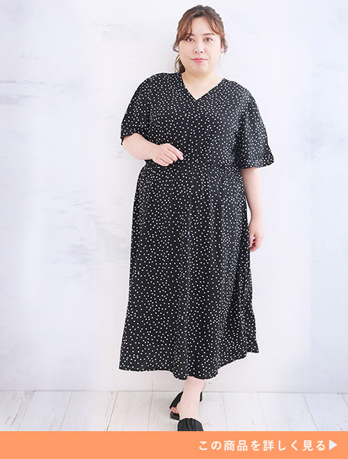 ウエストをシェイプしたドット柄の黒ワンピースを着る女性