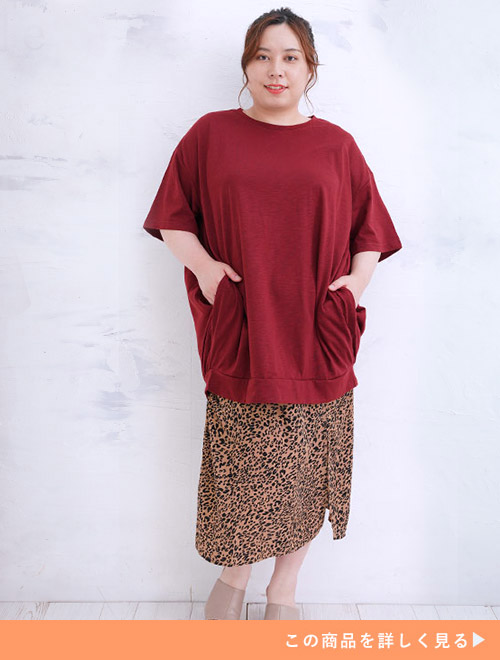 ワイン色のコクーンチュニックTシャツを着て、ヒョウ柄のスカートを履く女性