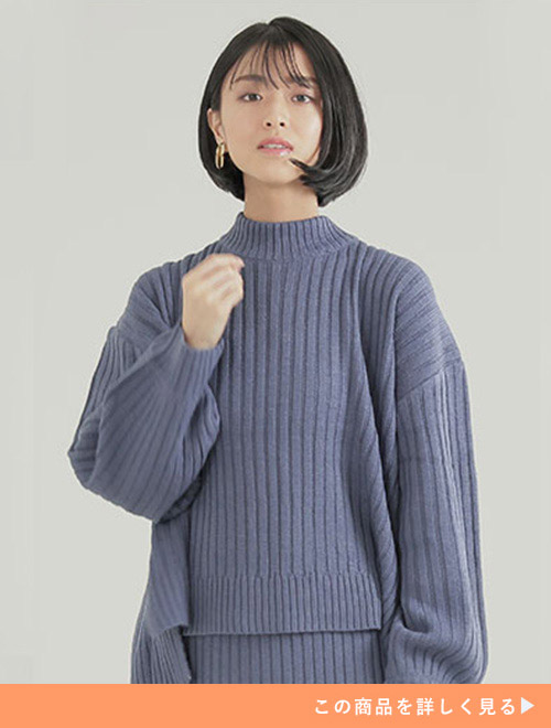 くすみブルーのニットのセットアップを着る女性