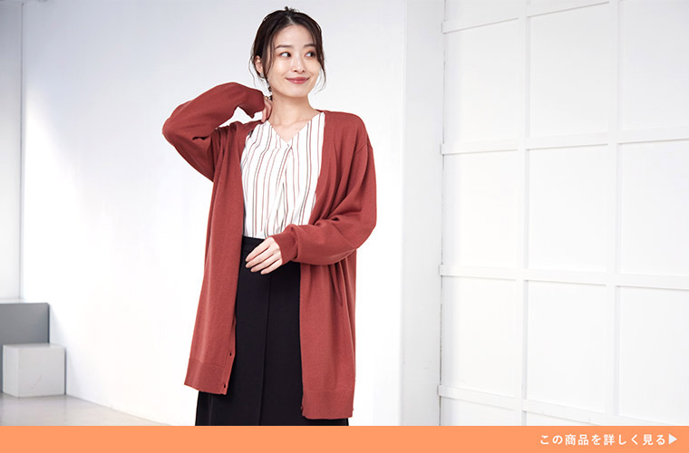 ストライプ柄の白トップス×黒ボトムに、ココアオレンジ色のロングカーディガンを羽織る女性