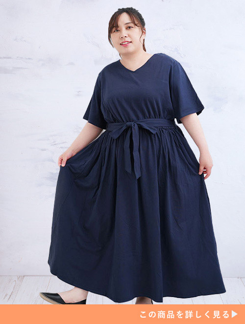 ネイビーのマキシ丈ロングワンピースを共布ベルトでウエストマークして着る女性