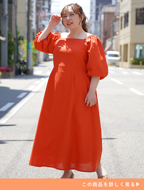 オレンジ色のスクエアネックのロング丈ワンピースを着る女性