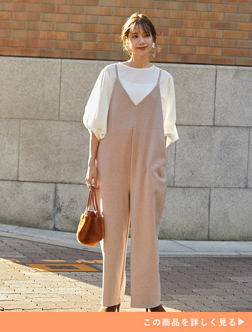 白ブラウスにグレージュ色のオールインワンを重ね着する女性