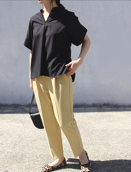 黒のシャツブラウスに、くすみイエローのテーパードパンツを履き、足元にはレオパード柄シューズをコーディネート