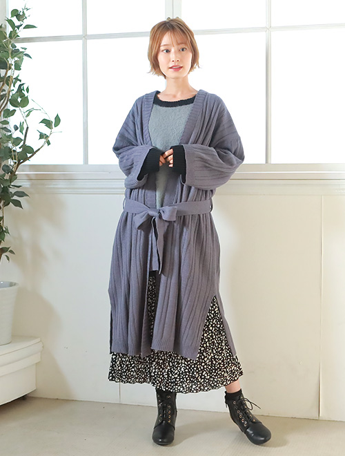 ニットと柄スカートのコーデに、ブルーグレーのロングカーディガンを羽織った女性