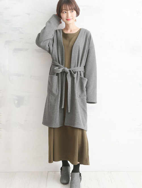 カーキのワンピースを着て、グレーのリボンベルトロングカーディガンを羽織る女性